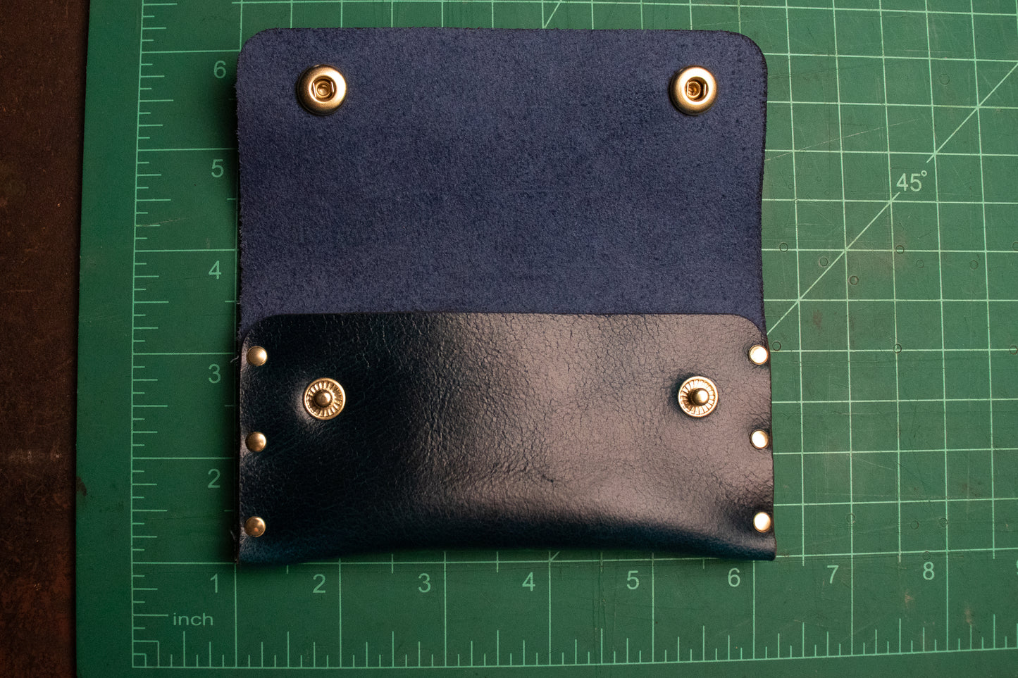 Leather card pouch on measuring table. Approximately 5 inches long and 5 inches tall with the front flap open.