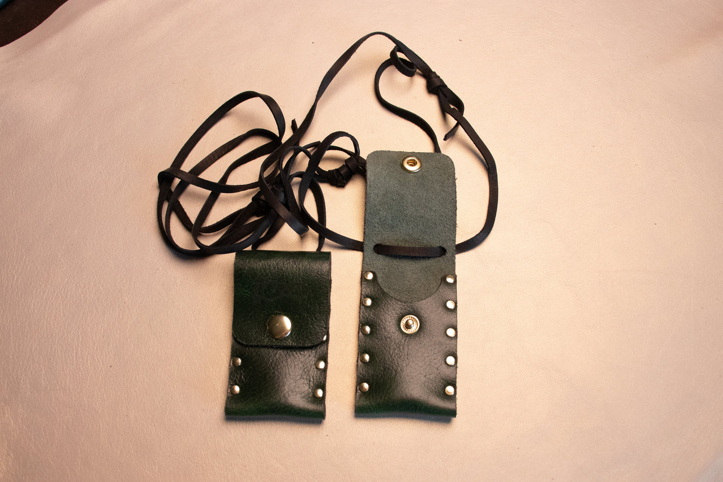 Two Green leather riveted thumb drive necklaces one is open.